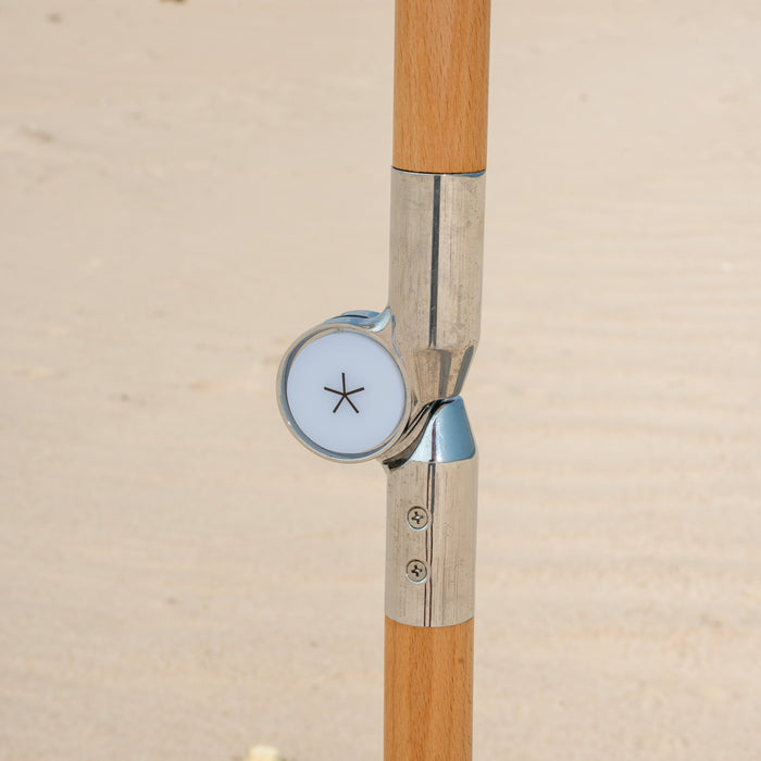 Close-up of a beach umbrella with a wooden shaft against a desert landscape.