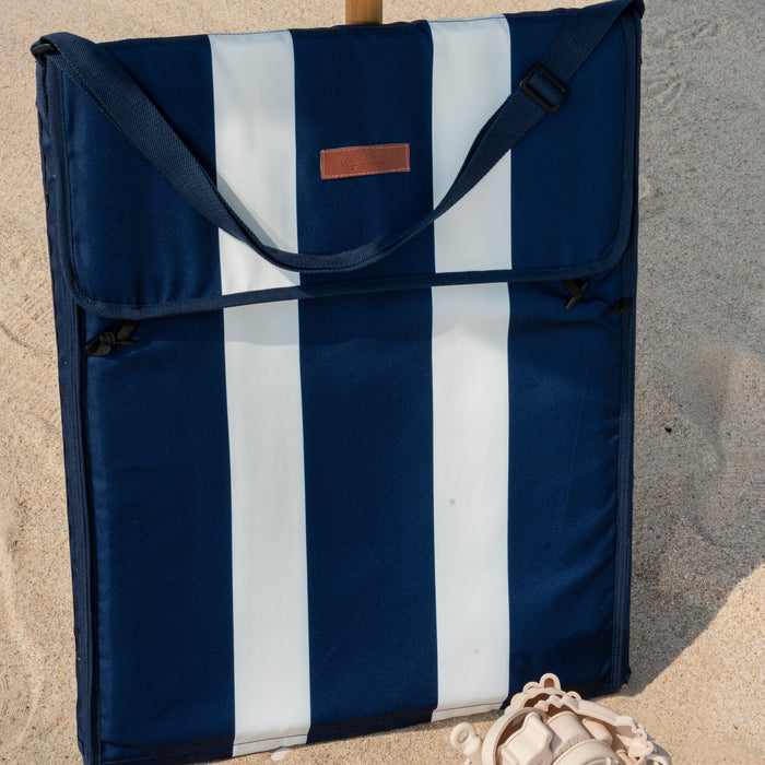 Navy and white striped folded beach mat on a sandy beach