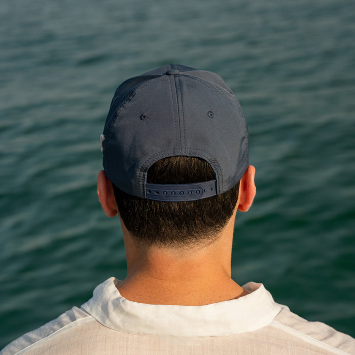 Person wearing a cap looking out at the ocean
