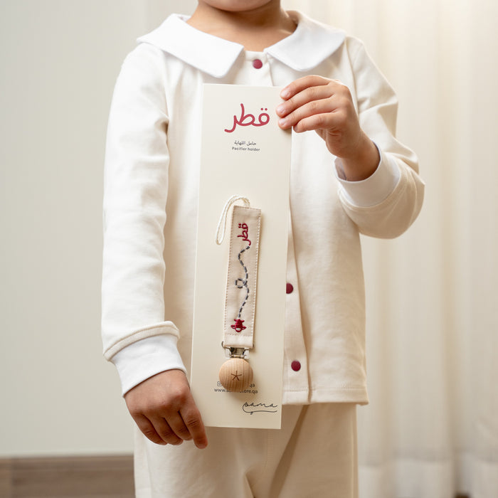 Child holding a Baby pacifier holder with product packaging