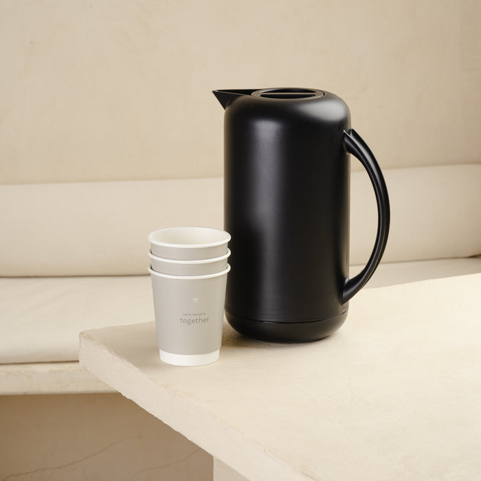 Black electric kettle or black vacuum jug on a white surface with an aesthetic background