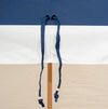 Blue and white striped beach umbrella on a wooden stand against a clear blue sky.