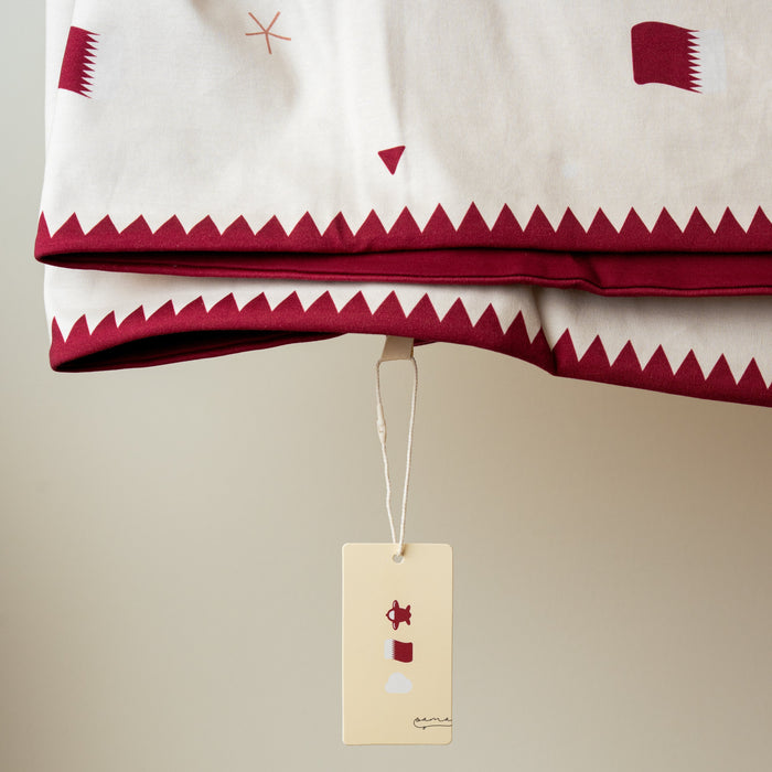 Baby blanket with geometric patterns with Qatar flag and a Sama tag on a beige background