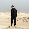 Person wearing Qatar Sweater Trouser Set - Classic Black back full set standing in a desert landscape with a clear sky