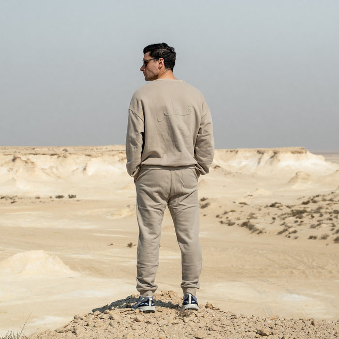 Person wearing Qatar Sweater Trouser Set - Sama Beige back standing in a desert landscape with a clear sky