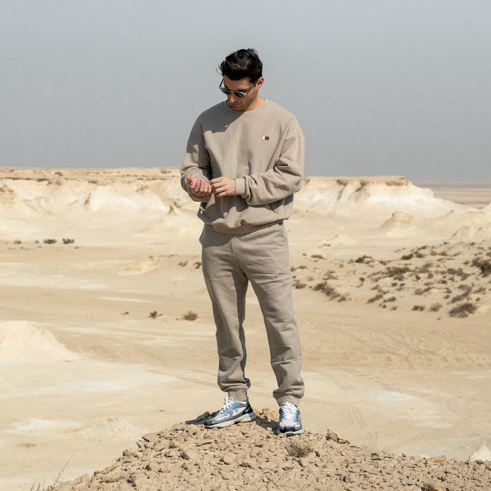 Person standing on a sandy hill in a desert landscape with Qatar Sweater Trouser Set - Sama Beige