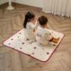 Two children sitting on a Qatar baby blanket with teddy bears in a room with wooden flooring and white curtains.