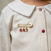 Close-up of a person wearing a white coat with a Qatar charms - baby safety pins