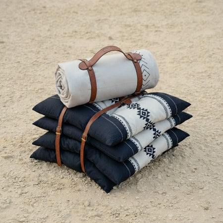 Sadu Cushion Set  with leather straps with rolled Sadu carpet on a sandy surface