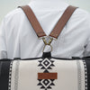 Person wearing a backpack style with a geometric pattern and brown leather straps.