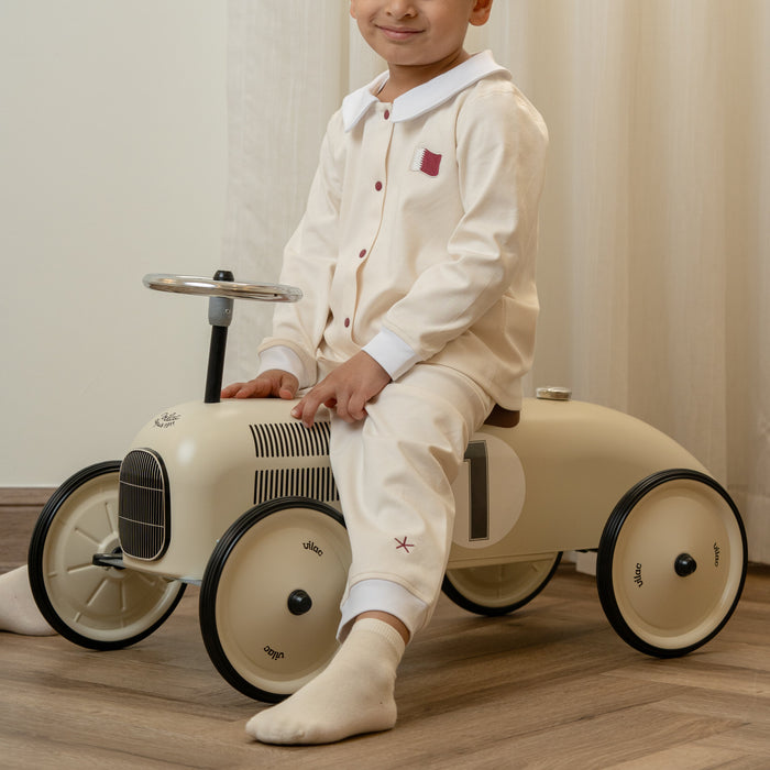 Child sitting on a toy car with a plain background